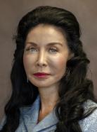 Portrait of a woman with long, dark hair wearing a gray top, looking directly at the camera against a neutral background.